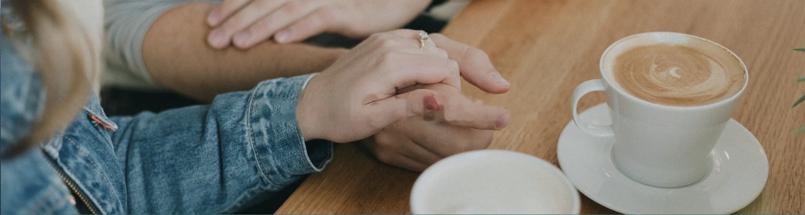 Two people holding hands across a caf&eacute; table